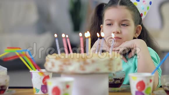 一个小女孩看着有蜡烛的蛋糕很伤心视频的预览图