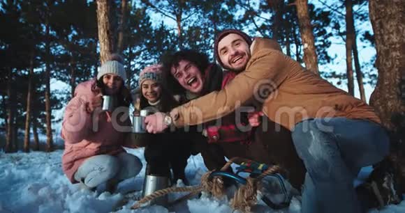 镜头前的大群朋友多民族享受时光在冬日的森林里喝点热的视频的预览图