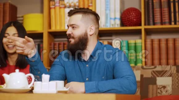 坐在咖啡馆里说话打手势的嬉皮士男子他旁边坐着一位亚洲面孔的朋友视频的预览图
