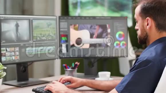 在他的双屏设置上工作的内容创建者的肩膀镜头视频的预览图