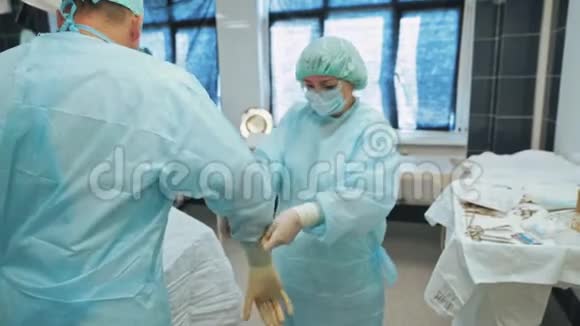 护士在手术前帮助医生在手术室穿无菌衣服视频的预览图