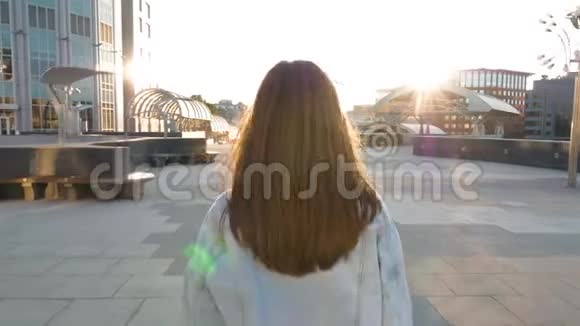 在日落时分一个棕色头发的女人沿着一条空荡荡的街道朝太阳走去视频的预览图