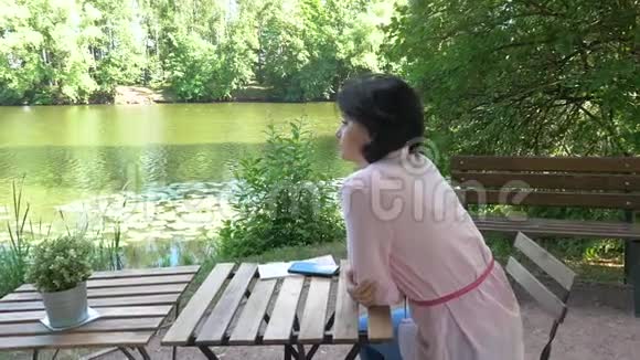 中年妇女在池塘边休息坐在一张桌子旁视频的预览图