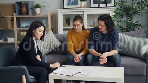房地产商与购房者讨论房地产契约夫妻双方在室内餐桌上视频的预览图