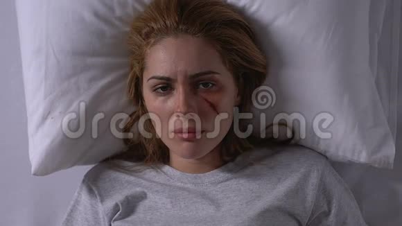 绝望的女人受伤的脸躺在床上看着镜头受害者视频的预览图