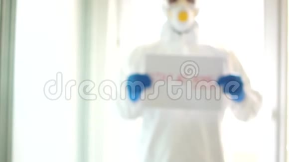 穿着防护服的人拿着一个牌子说呆在家里冠状病毒covid19的流行隔离和自我视频的预览图