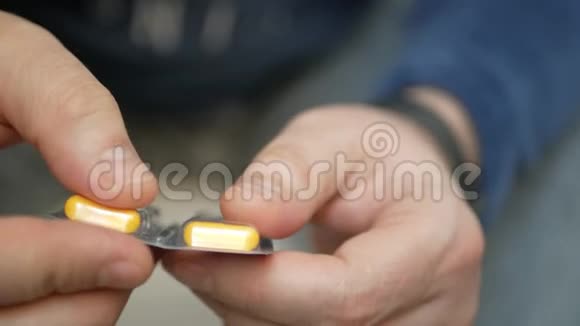 男人用手从水泡包里拿药丸特写男性手倒白橙圆片手里拿着药剂丸氟视频的预览图