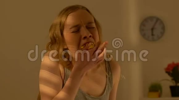 沮丧的少女贪婪地嚼着甜蛋糕暴饮暴食暴食视频的预览图