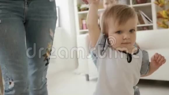 近距离观看小宝贝女儿手牵着妈妈的手在室内缓慢运动视频的预览图