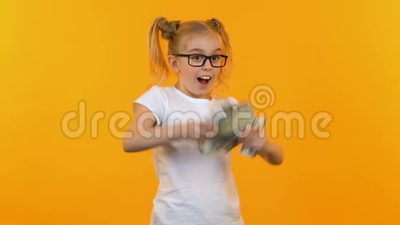 戴眼镜的有趣女孩把钱扔到空中聪明的孩子得到津贴视频的预览图