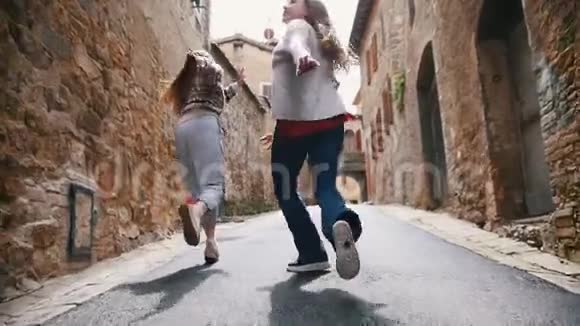 两个年轻的笑女跑到巷子里视频的预览图