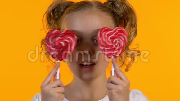 微笑着的小女孩开心地闭上眼睛与心形棒棒糖童年视频的预览图