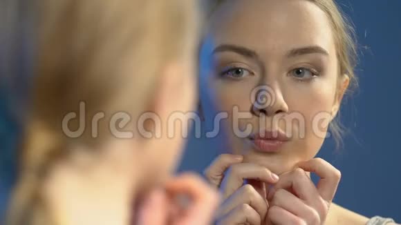 女青少年看着镜子发现粉刺皮肤不完美视频的预览图