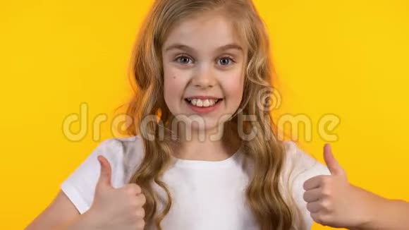 兴奋的女孩在背景上伸出大拇指和眨眼成功的快乐孩子视频的预览图