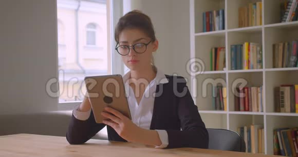 年轻漂亮的高加索女商人戴着眼镜的特写镜头用平板电脑看着镜头兴高采烈地笑着视频的预览图