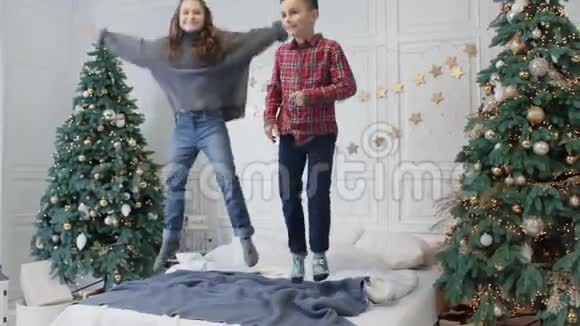 有趣的孩子在双人床上参加跳跃派对微笑的女孩在大床上跌倒视频的预览图