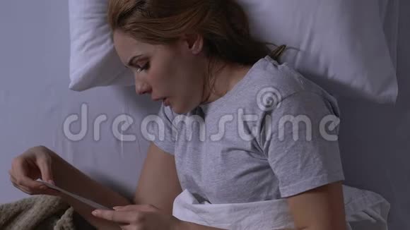 哭泣的年轻寡妇躺在床上看着照片思念的丈夫俯视视频的预览图