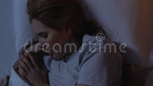 哭泣的女人晚上躺在床上抱着头患有偏头痛视频的预览图