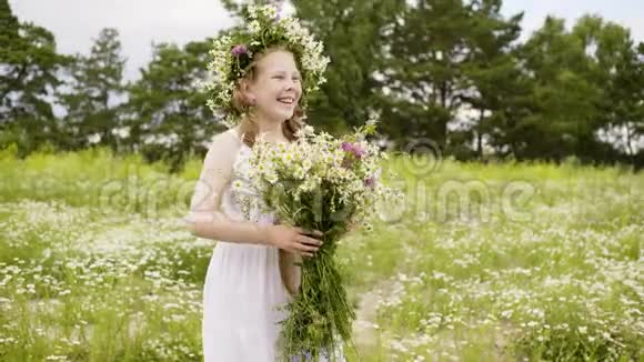 快乐的女孩穿着白色连衣裙花束和雏菊花环在花甸上视频的预览图