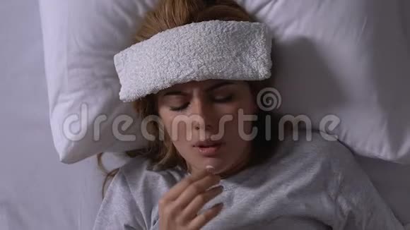 女人躺在床上额头上有毛巾吃药感冒生病视频的预览图