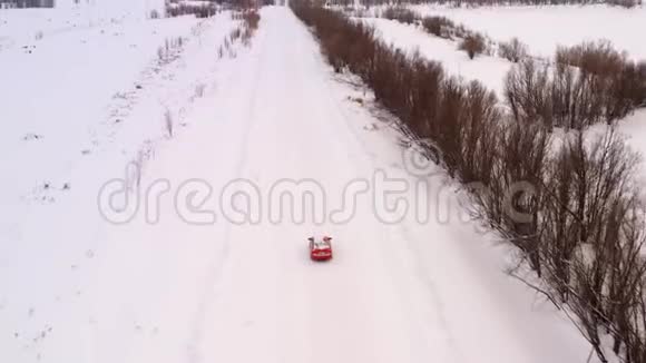 一辆车正沿着一条冬天下雪的乡村道路行驶从无人驾驶飞机上俯瞰视频的预览图