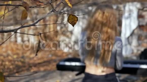 年轻性感的女人在秋天的街上玩合成器光着屁股音乐风格咕噜乐器流行歌曲视频的预览图