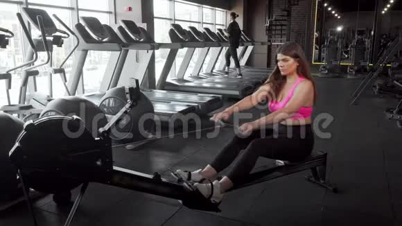 漂亮的曲线美女运动员在健身房锻炼赛艇机视频的预览图