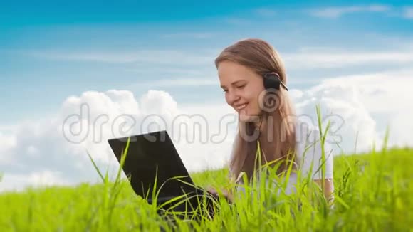 绿色草地上有笔记本电脑的女人视频的预览图