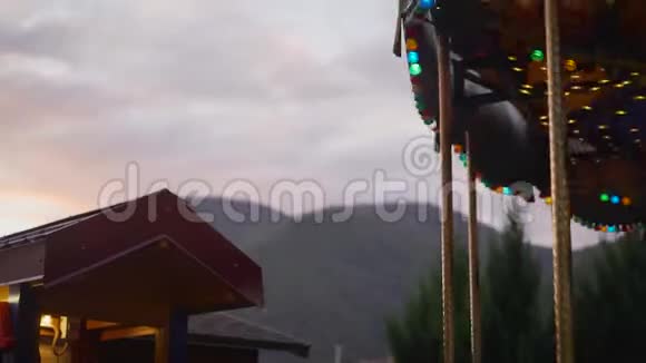 旋转木马在夕阳和群山的背景下孩子们旋转木马在山上旋转视频的预览图