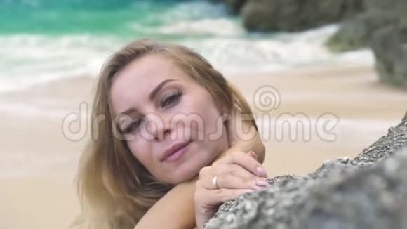 肖像美丽的女人微笑着望着岩石海滩上的镜头面对夏天留长发的快乐女人视频的预览图