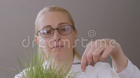 一个中年妇女眼睛戴着眼镜用指甲剪刀修剪草坪视频的预览图