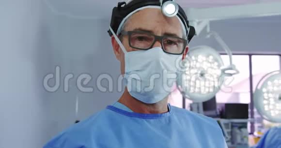 高加索男医生在医院手术室站在手术前照灯中的特写镜头视频的预览图