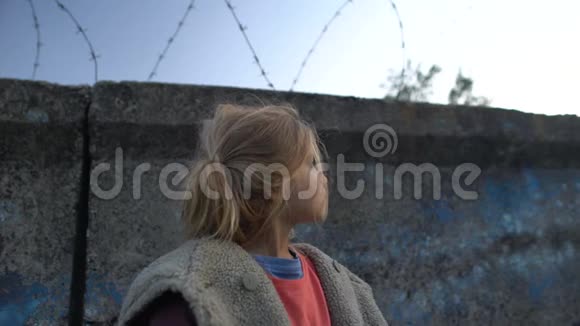 站在铁丝网前满脸泥泞的小女孩难民营中的战争儿童视频的预览图