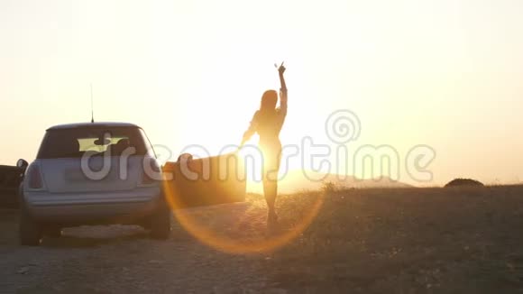 两个苗条的年轻女子下车举起双手到达最后一缕夕阳的阳光视频的预览图
