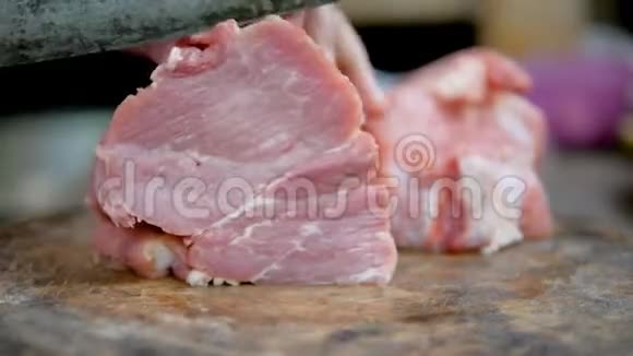 女人的手用菜刀把猪肉切片放在砧板上煮熟视频的预览图
