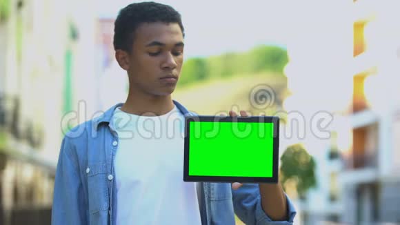 严肃的混血少年指着绿色屏幕平板电脑工作应用视频的预览图
