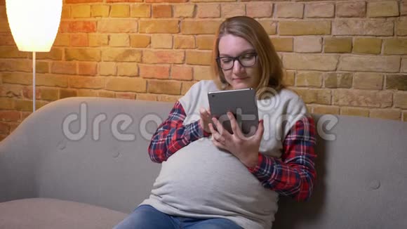 使用平板电脑拍摄年轻孕妇的特写镜头并显示绿色彩色屏幕拍摄时开心地微笑视频的预览图