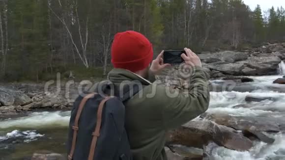 旅行者戴着红色帽子背着一个背包停下来拍了一张山河的照片旅行和视频的预览图