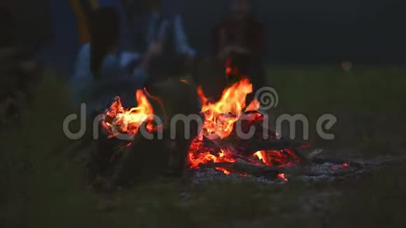晚上篝火露营的人背景在草地野炊在黑暗中篝火橙色和黄色的火能视频的预览图