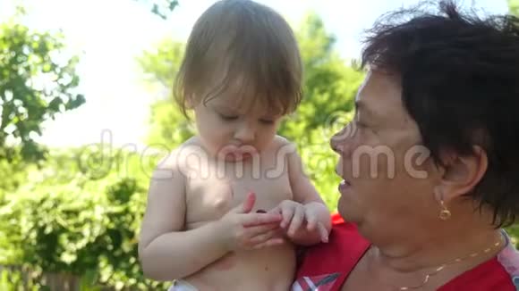 孙女在夏天在花园里喂一个成熟的樱桃祖母宝宝喂妈妈红樱桃婴儿视频的预览图