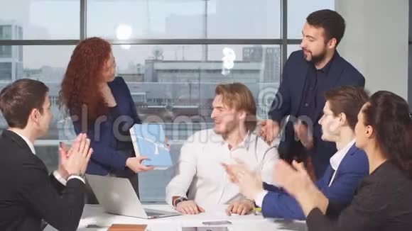 一群商人在办公室祝贺同事他们拍手微笑视频的预览图