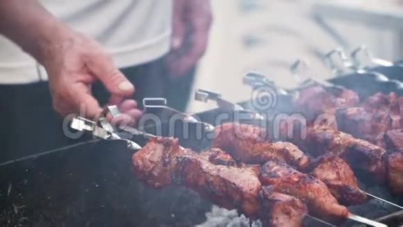 把烤肉串放在烤架上烧烤烹饪肉和火的烟雾野餐特写慢动作视频的预览图