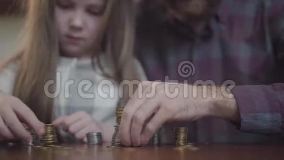不可辨认的男人穿着衬衫小女孩集中坐在桌子旁数着硬币父亲和视频的预览图