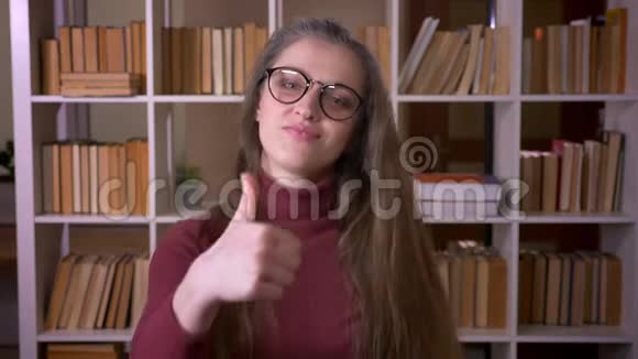 戴着眼镜的年轻白种人女学生的特写照片她竖起大拇指开心地笑着看着镜头视频的预览图