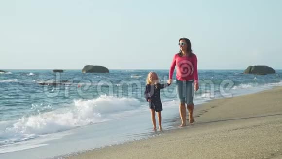 带着妈妈走在海滨的小女孩视频的预览图