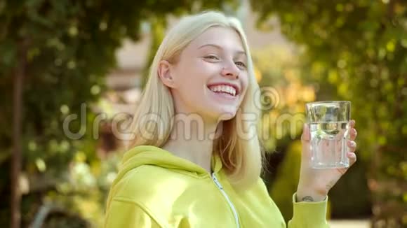 玻璃水的女人的面部肖像年轻女子喝水把金发女孩的画像贴起来清洁卫生视频的预览图