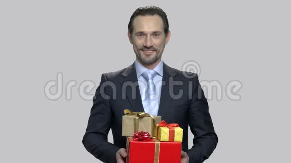 商人拿着灰色背景的礼盒视频的预览图