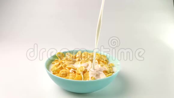 在一个蓝色盘子里玉米片倒牛奶在白色背景上慢镜头拍摄视频的预览图