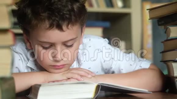 男孩把头伸进手里读着厚厚的书翻着书页视频的预览图