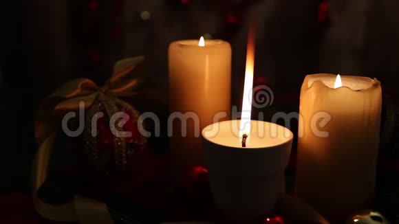 圣诞节的气氛三支点燃的蜡烛一支在前景上有一个大火焰红色和金色的球脱钩的球缎子金视频的预览图